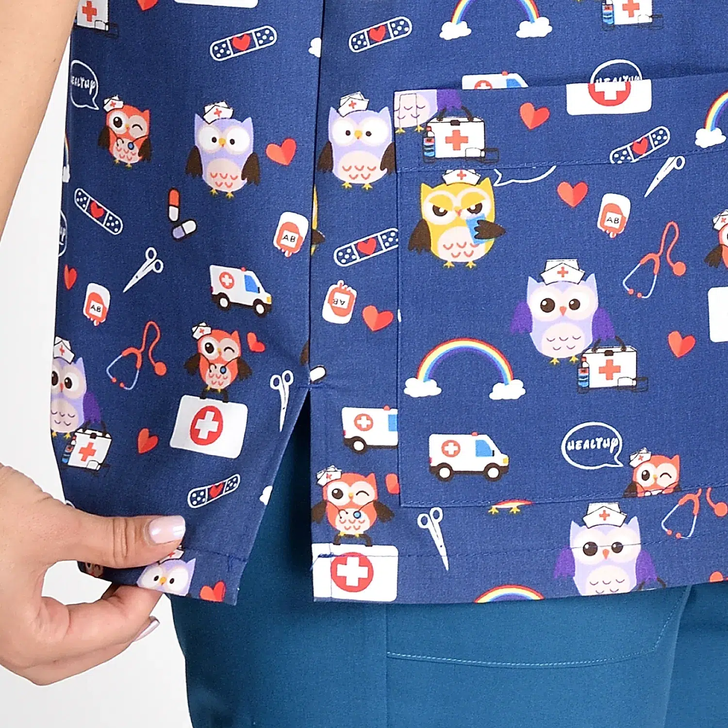 Close-Up View of Cartoon Print Women’s Medical Scrub Top in Blue with Pockets Close-up of a women's cartoon print scrub top in blue with side pockets, featuring a playful design and practical storage for healthcare professionals.