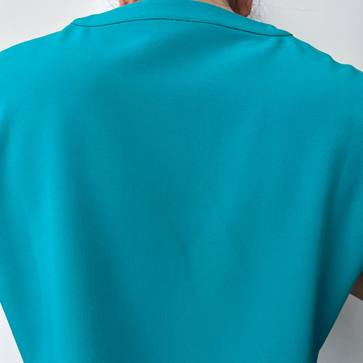 Close-up of teal surgical gown top showing zippered pocket, perfect for secure storage in healthcare settings.
